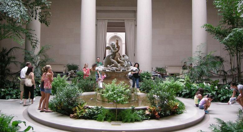 Family with children mill around the interior gardens of the West Building.