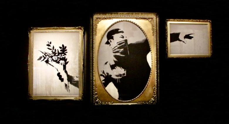 Installation view of Banksy: Genius or Vandal? in Los Angeles, 2021-2022 featuring "love is in the air" sectioned into frames.