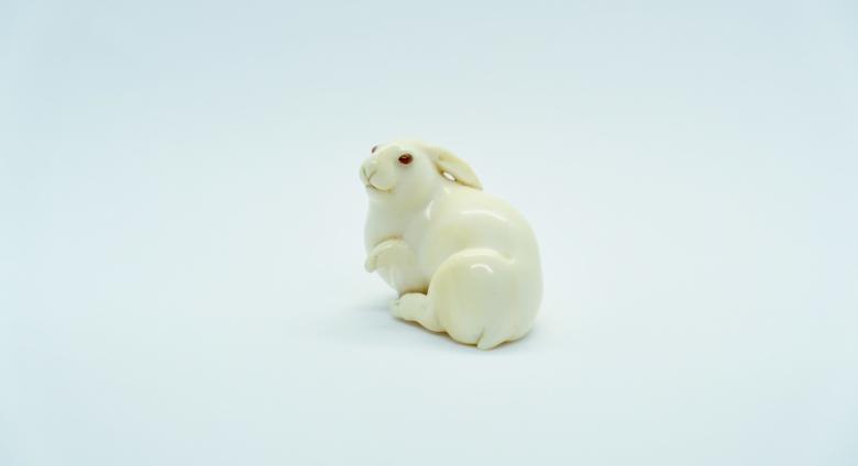 Recumbent hare with raised forepaw, signed Masatoshi. Ivory, eyes inlaid in amber colored buffalo horn. Osaka, Japan, ca. 1880.