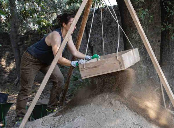 9758: Dana Zentgraf (excavator, PhD Student Christian-Albrechts-Universität Kiel) shakes soil through a sifter to look for finds that might otherwise be overlooked by the eye in the trench.