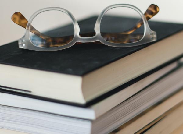 stack of books with pair of reading glasses on top