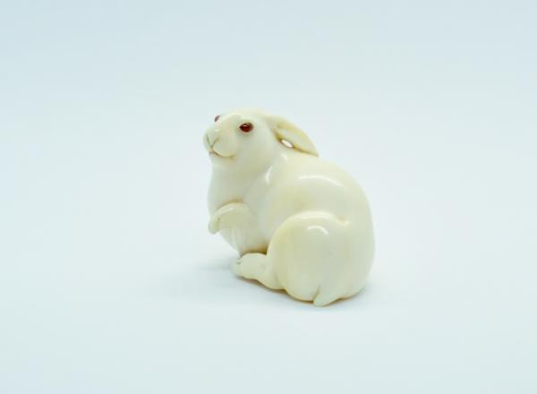 Recumbent hare with raised forepaw, signed Masatoshi. Ivory, eyes inlaid in amber colored buffalo horn. Osaka, Japan, ca. 1880.