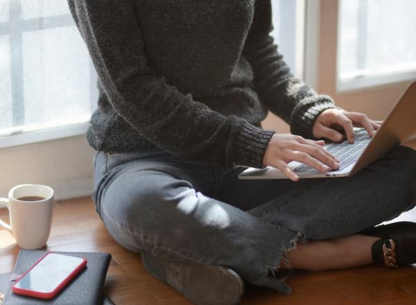 woman works on computer on the floor next to mug